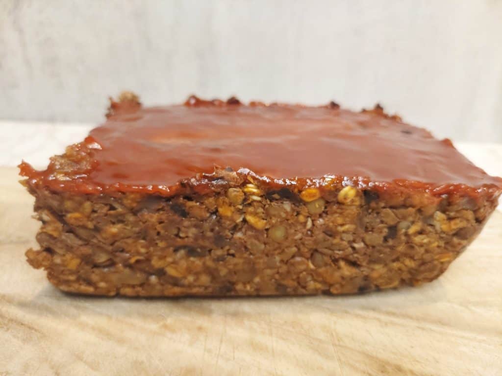 high protein lentil mushroom loaf with glossy glaze on a cutting board