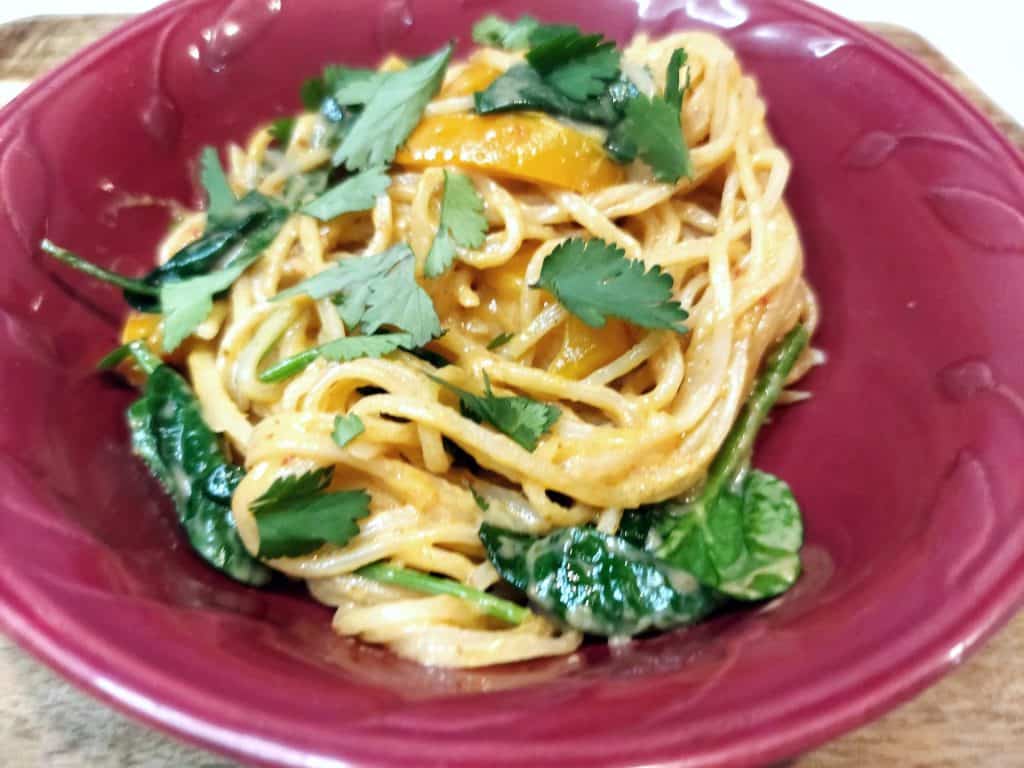 bowl of creamy vegan noodles with red bell pepper and fresh cilantro