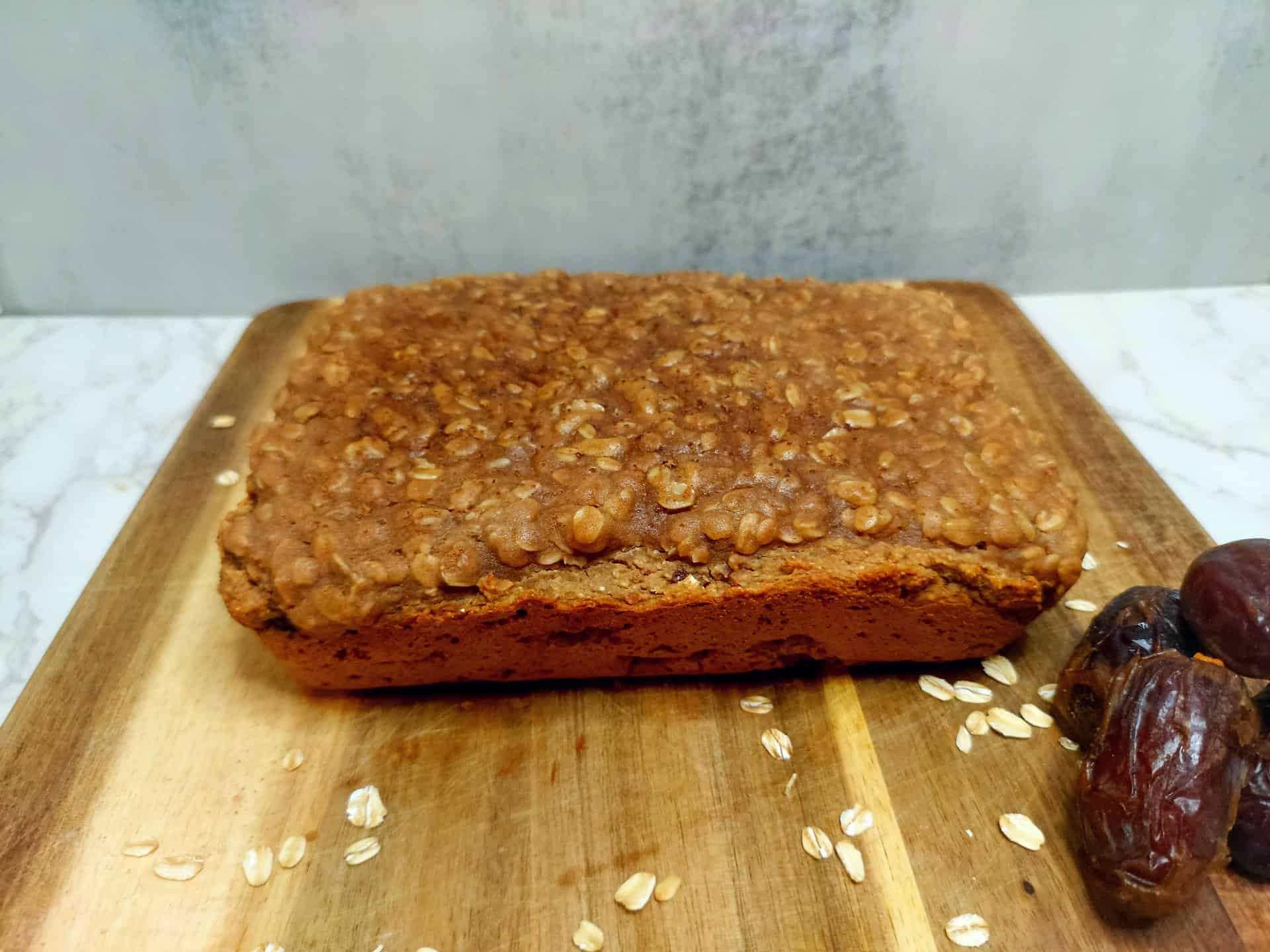 whole loaf of high protein date oat coffee cake with scattered oats and dates