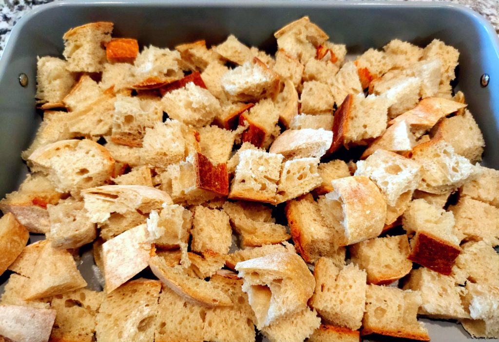 sourdough bread cubes arranged in greased baking dish for french toast casserole